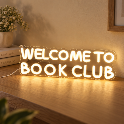 Warm-white Welcome to Book Club sign on a light oak surface